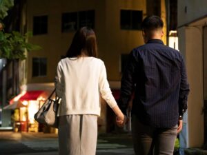 Back view of men and women holding hands in downtown at night
